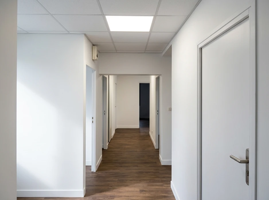 Couloir de bureau professionnel vide, murs blancs, sol en parquet stratifié wengé foncé
