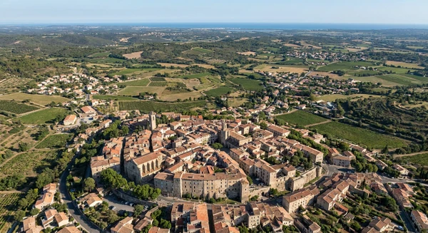 Photographie a&eacute;rienne ou vue panoramique de la r&eacute;gion de P&eacute;zenas dans l'H&eacute;rault, montrant le paysage typique de la r&eacute;gion (habitat urbain ou semi-urbain, vue d'ensemble des zones r&eacute;sidentielles et commerciales). L'image doit pr&eacute;senter une perspective claire du territoire couvrant la zone d'intervention de 50 km autour de Lignan-sur-Orb, sans texte, logo ou filigrane visible.