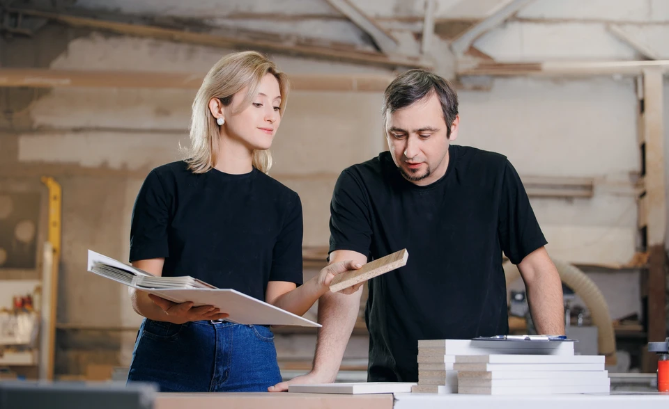 Artiste principal et apprenti charpentier avec un plan d'ensemble discutez d'un projet de construction de maison
